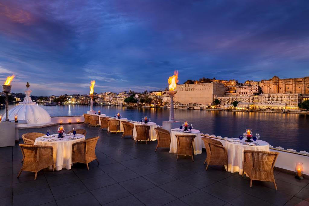 Rooftop dining terrace at Taj Lake Palace overlooking Lake Pichola and the City Palace at dusk
