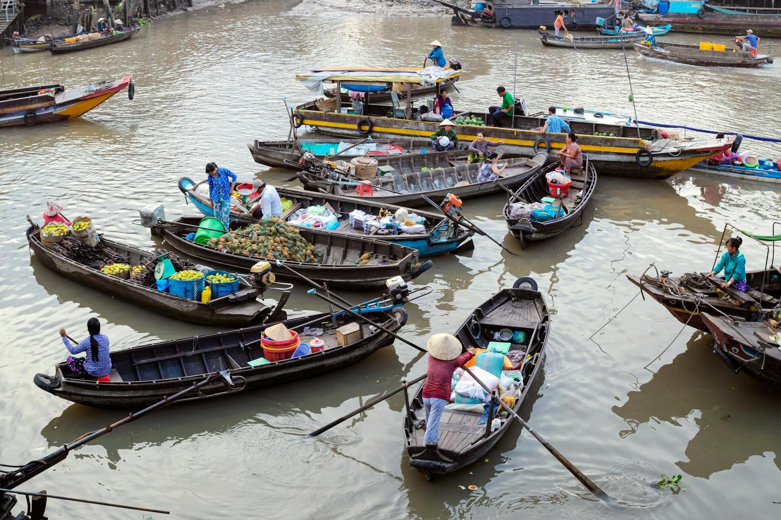 Vendors trading produce between narrow wooden boats at a floating market