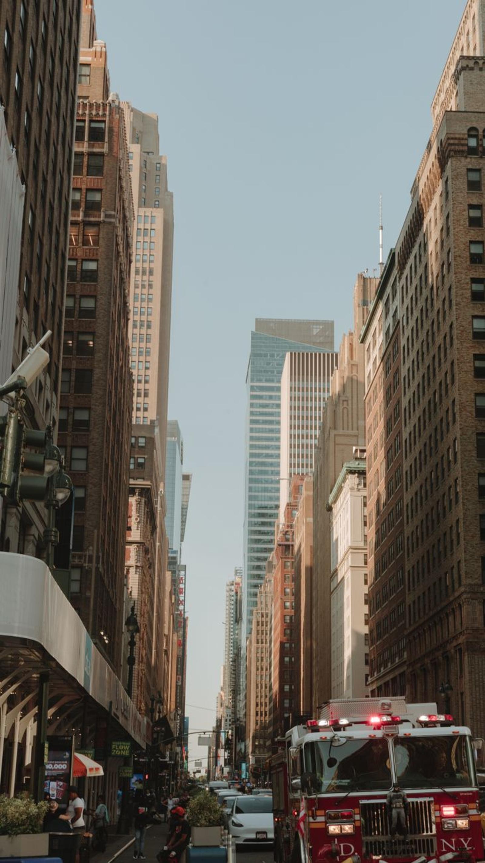 Fire truck driving down a narrow street between tall buildings