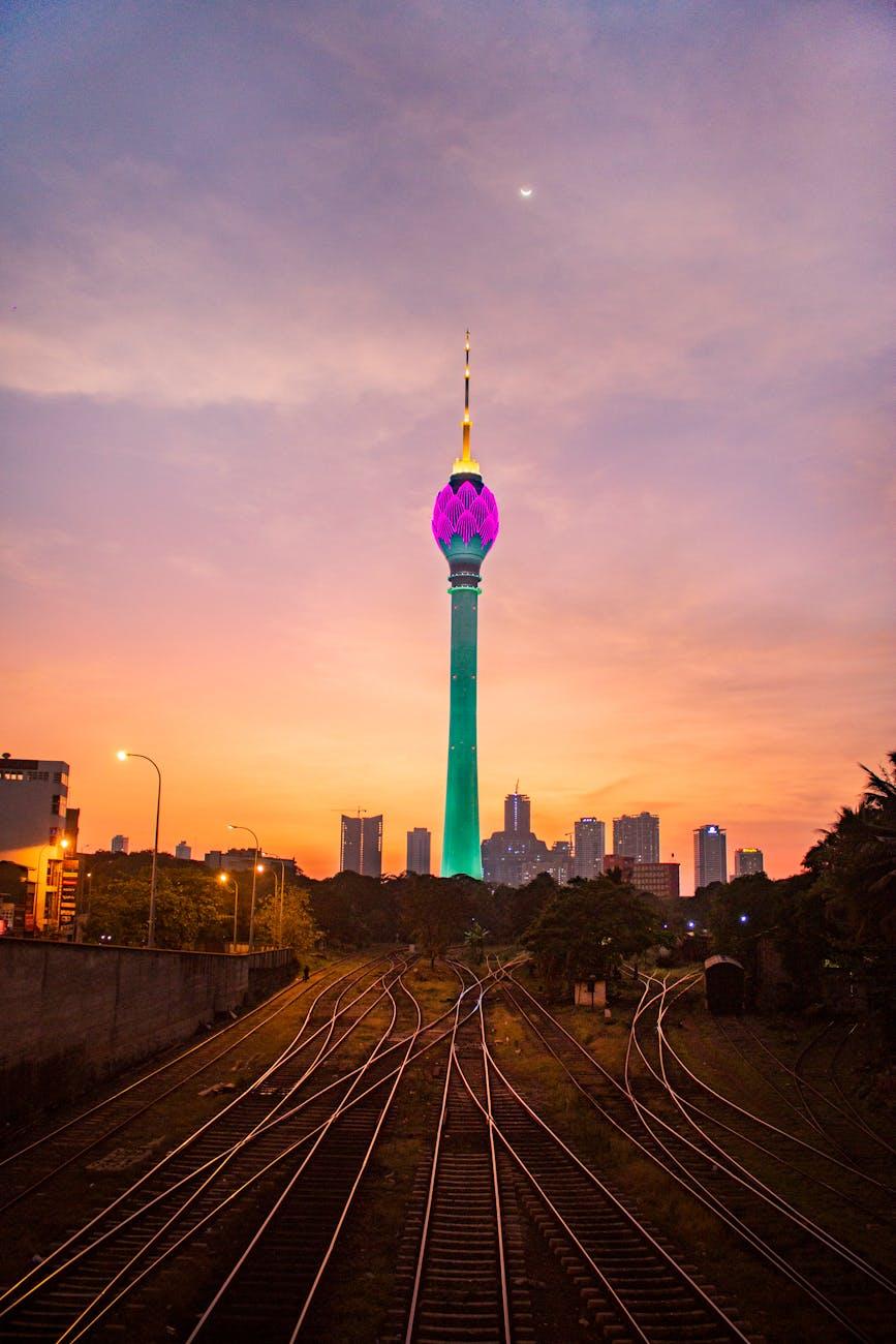 View of illuminated Colombo Lotus Tower at sunset with railway foreground in Sri Lanka