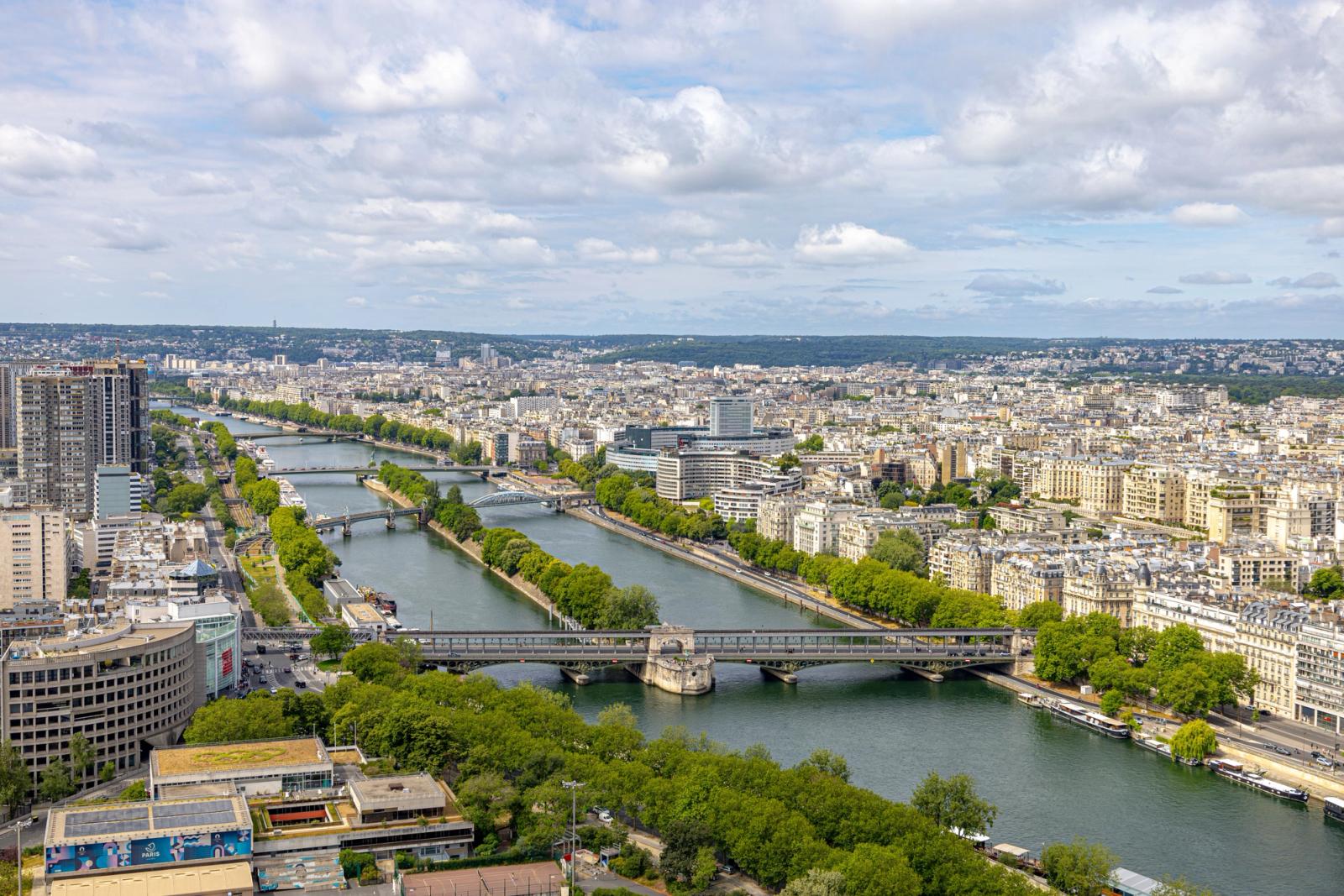 Scenic aerial view of the Seine River flowing through Paris, showing bridges and cityscape on a sunny day