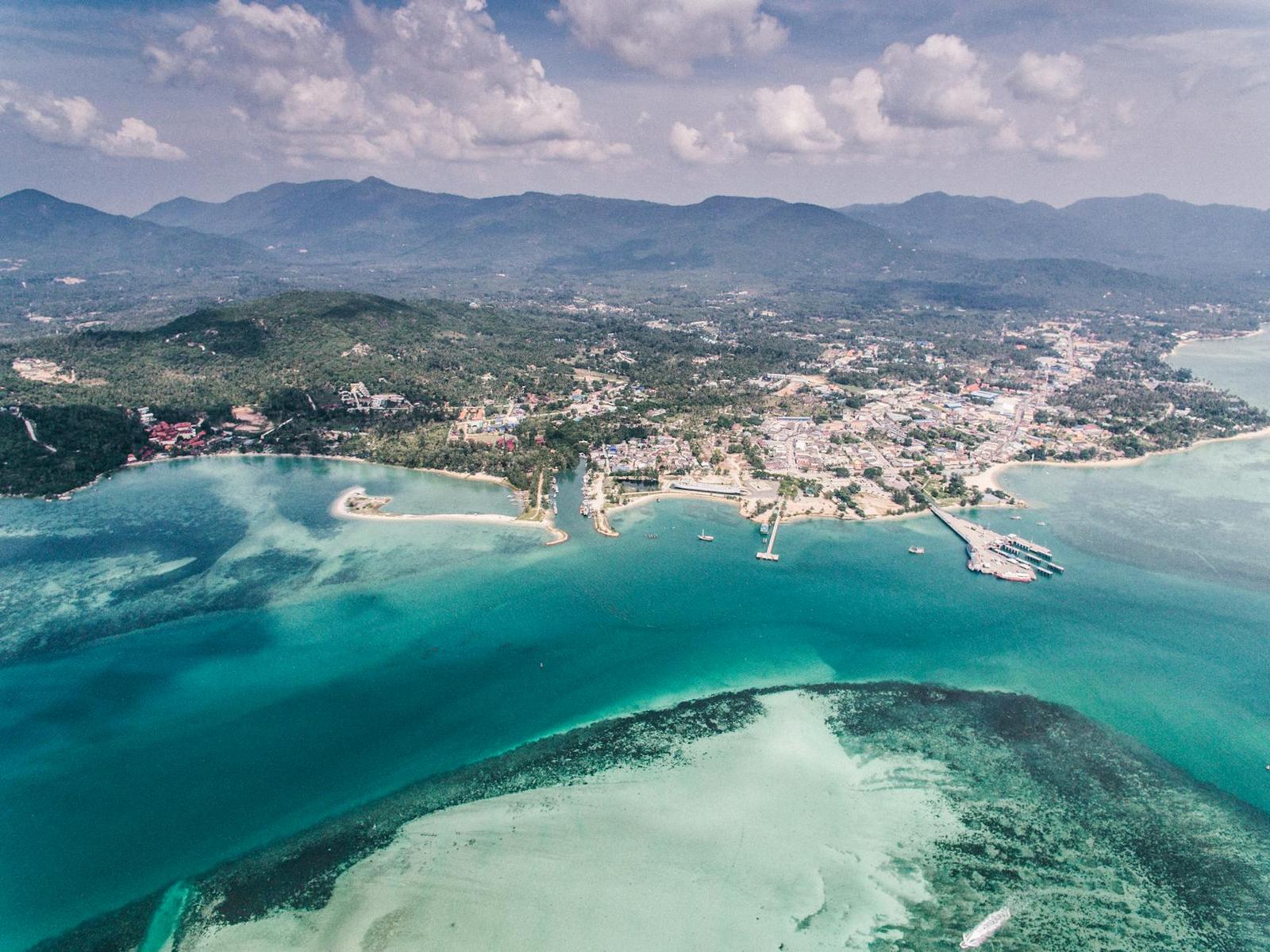 Aerial view of a coastal town where a coral reef meets forested hills