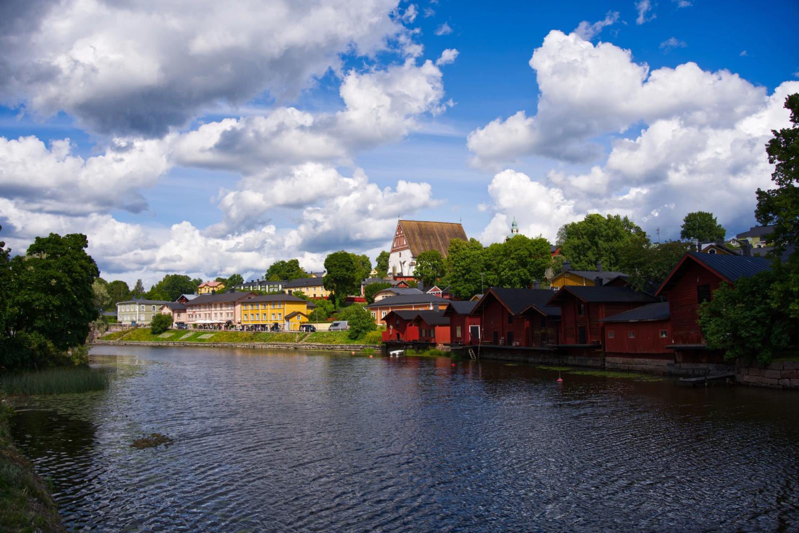 Charming summer view of Porvoo's historic riverside buildings, clouds overhead