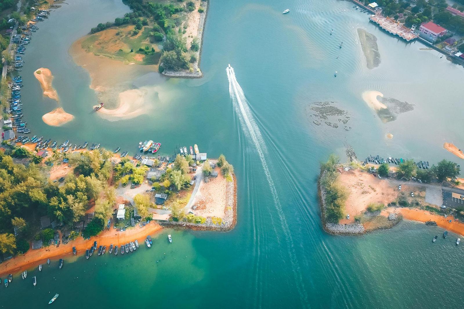 Aerial view of a boat crossing a river mouth between two sandy peninsulas