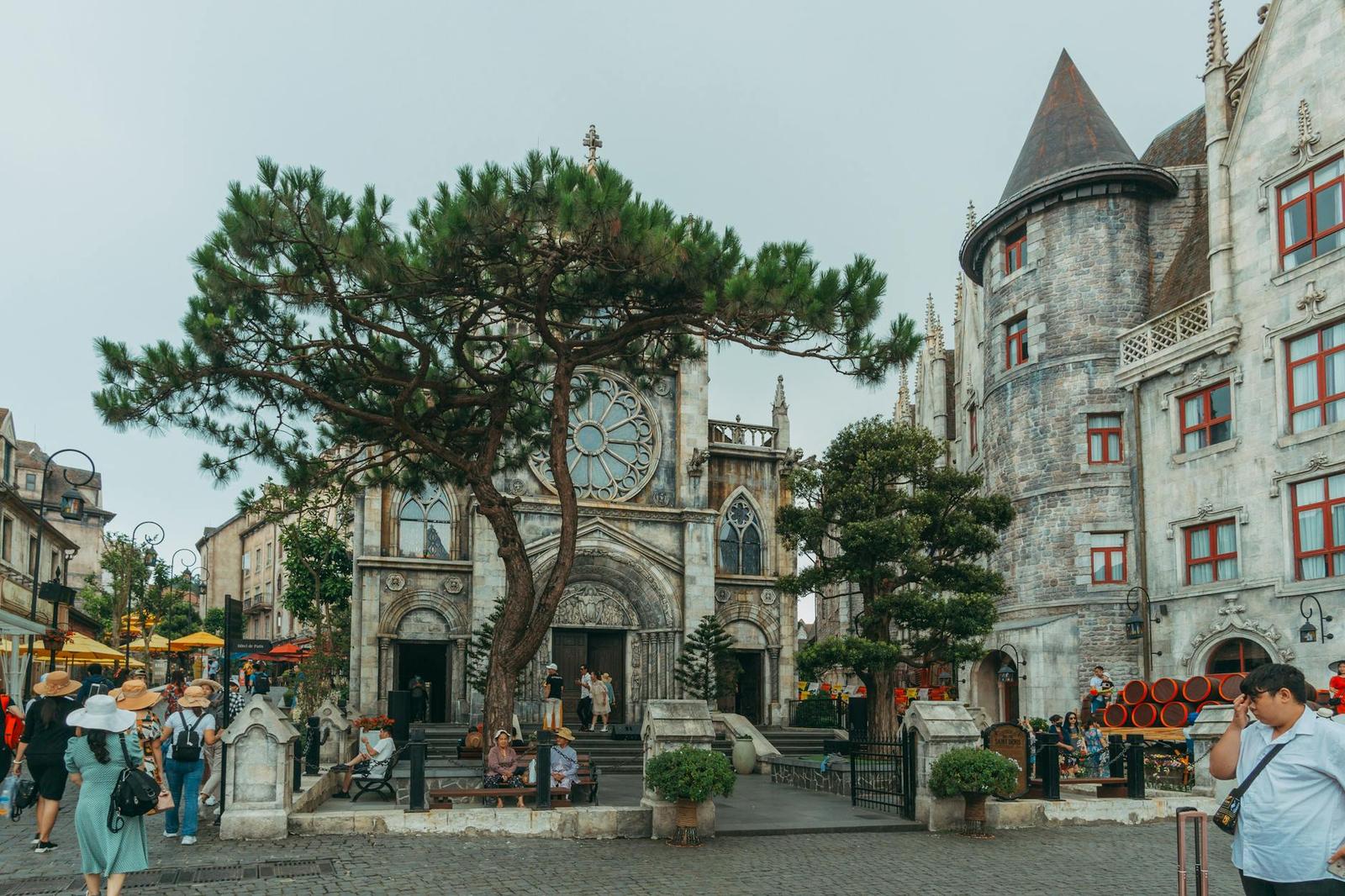 Visitors gathered in a European-style plaza beside a stone church and turreted building