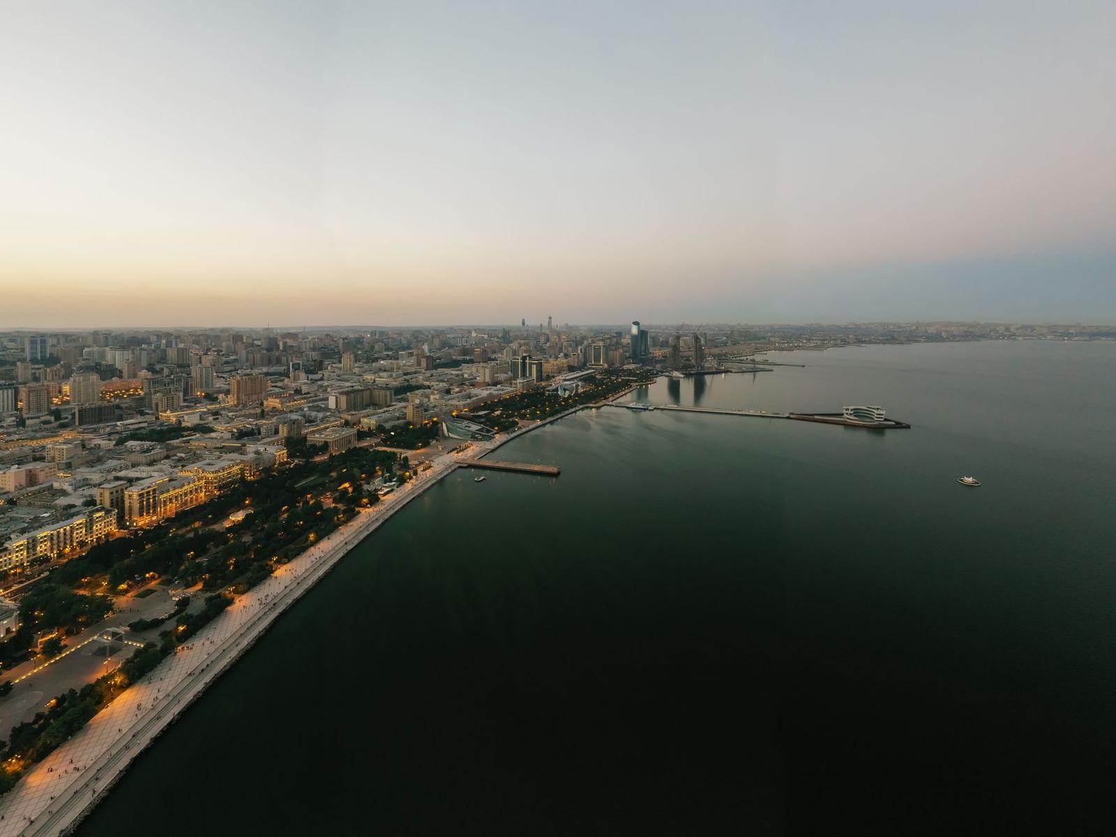 Aerial view of a coastal city curving along the shoreline at dusk