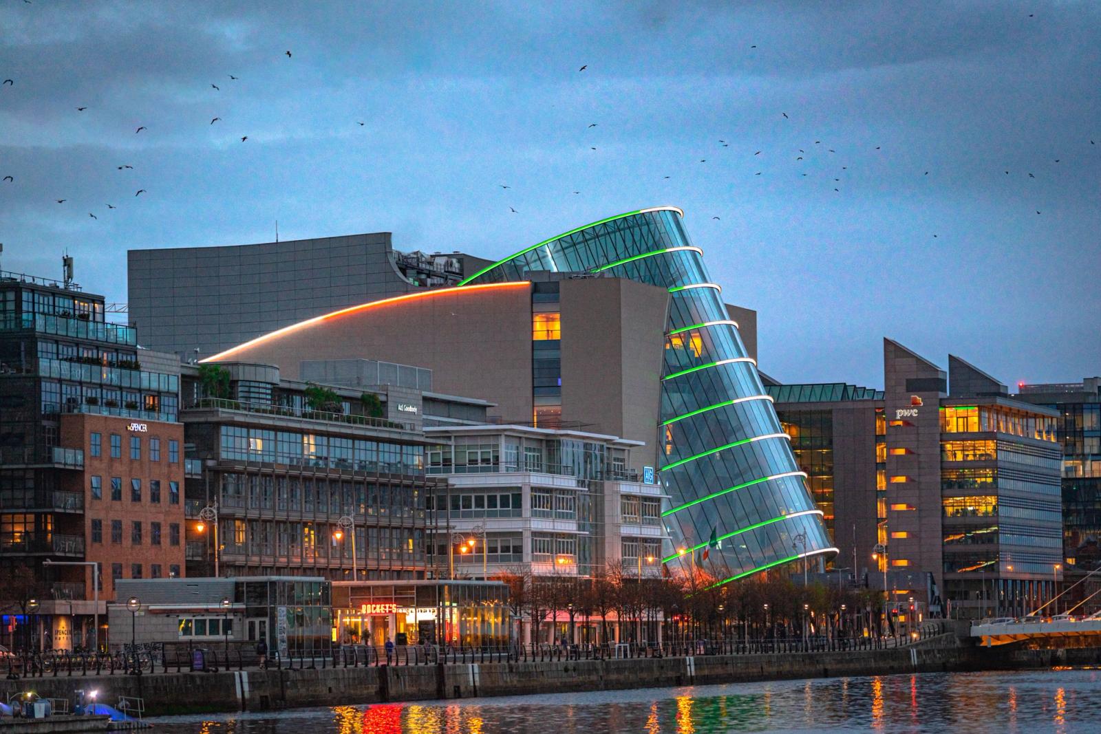 A stunning night view of the Dublin Convention Centre by the River Liffey, illuminated in vibrant colors