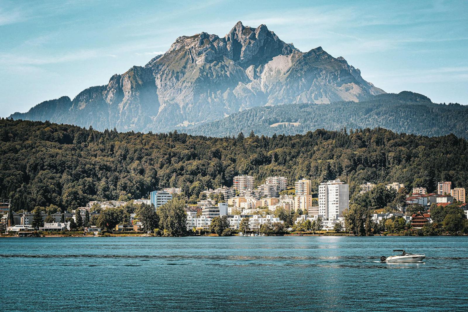 Cloud-wrapped peak seen across a lake from a wooded shoreline