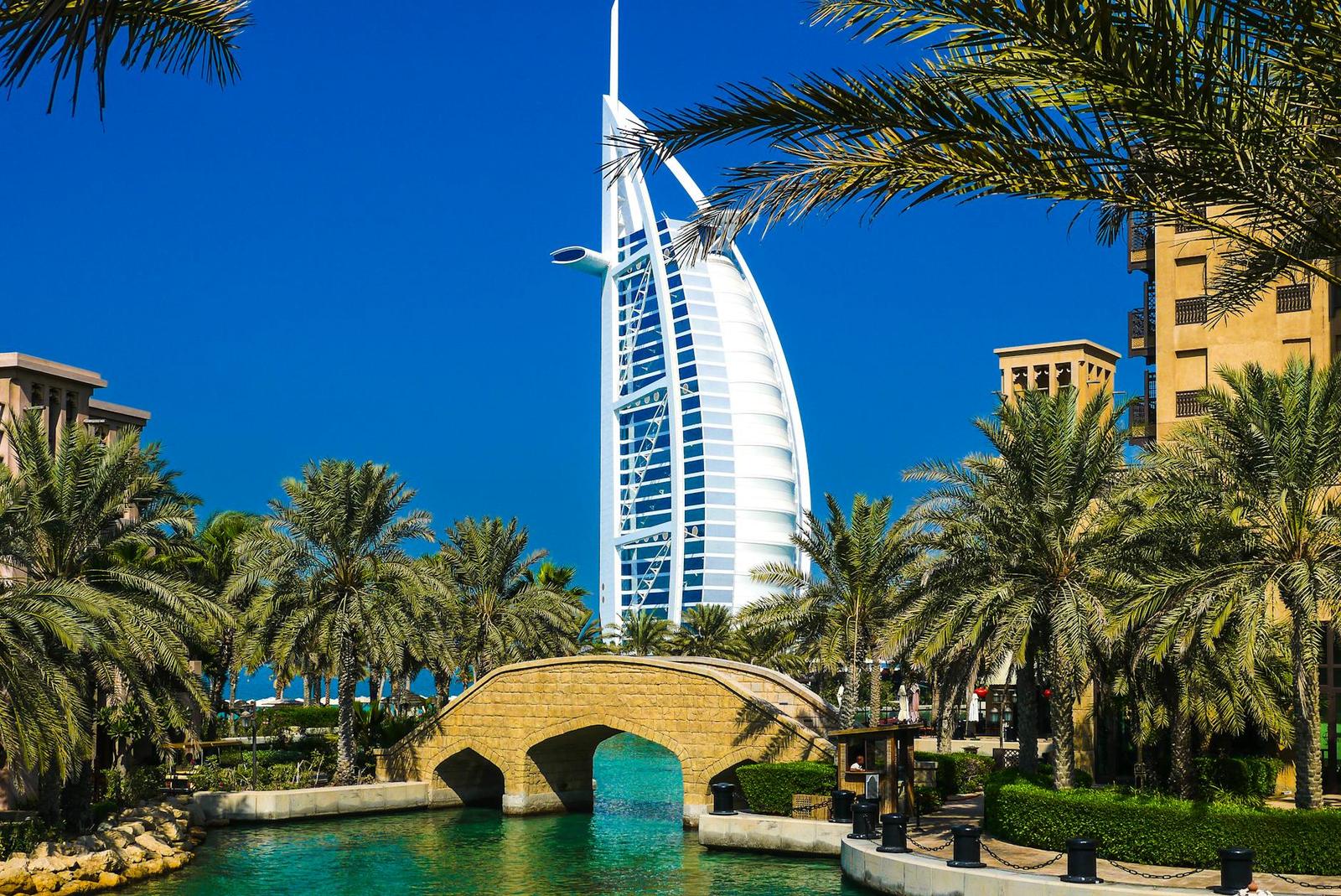Scenic view of Burj Al Arab surrounded by lush palm trees and clear blue sky in Dubai