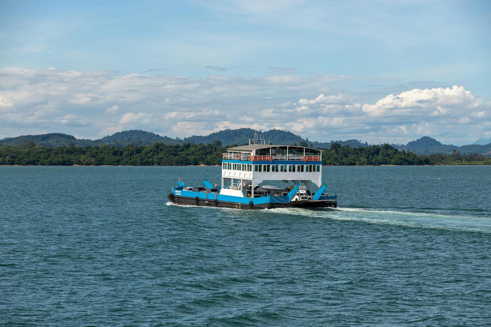 Passenger ferry traverses calm tropical waters with lush islands in the background under a clear blue sky