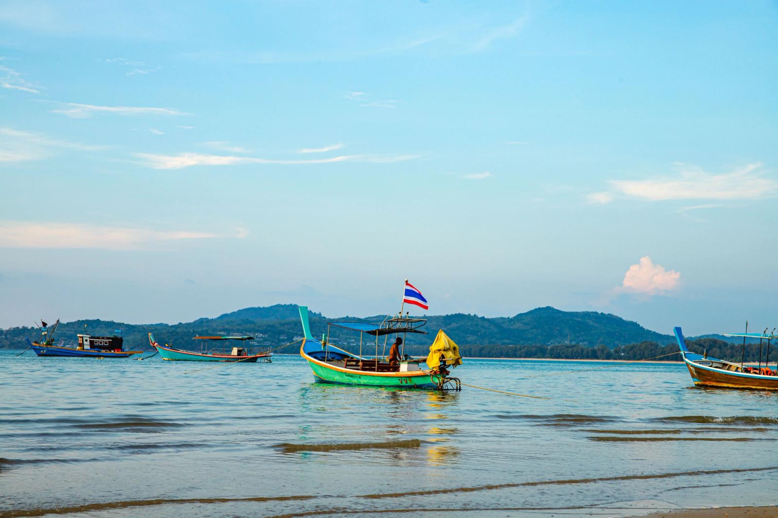 Traditional long-tail boats anchored on a tranquil sea in Phuket, Thailand during day time