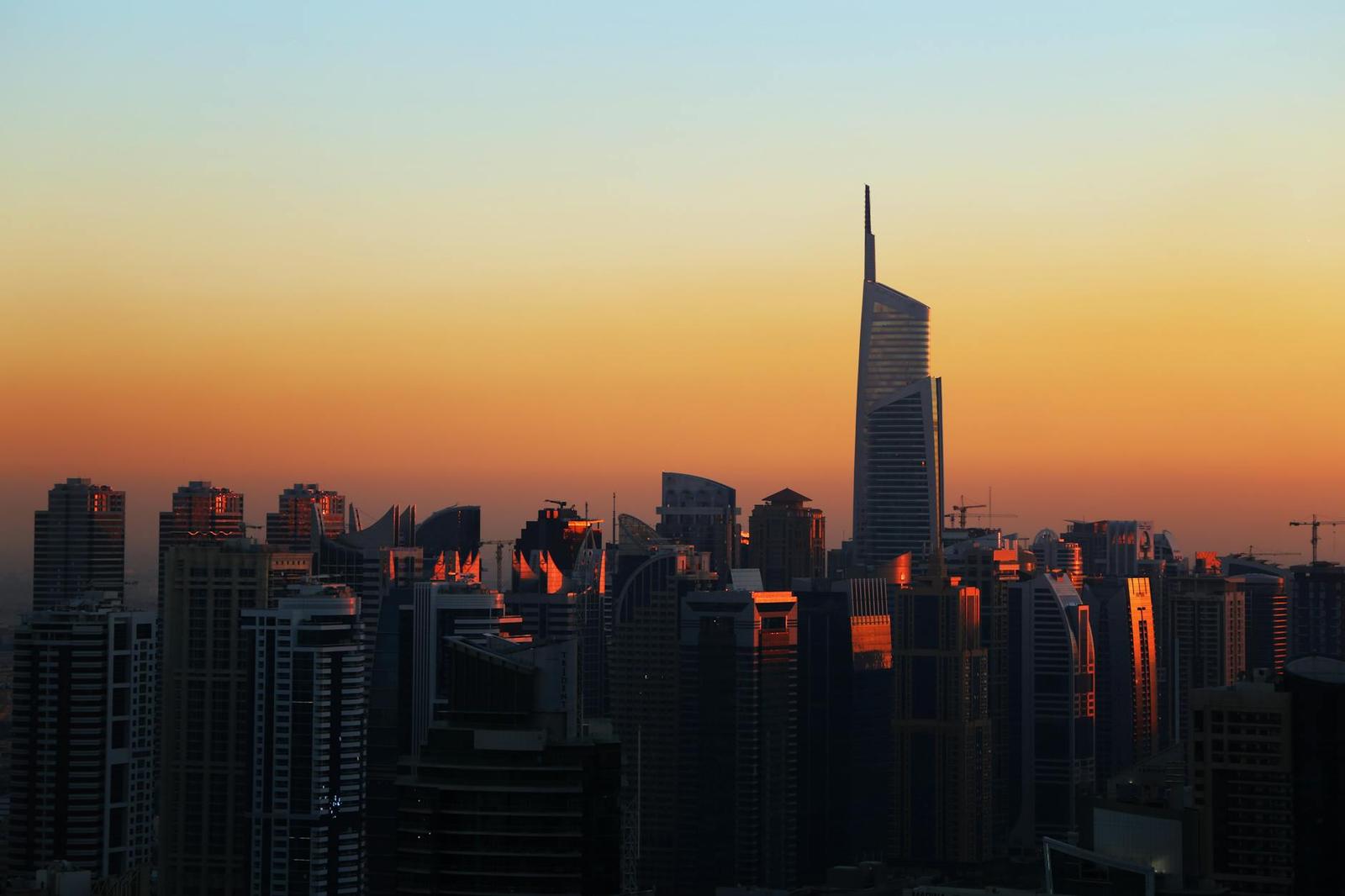 Twisted skyscraper rising above a marina skyline at sunset