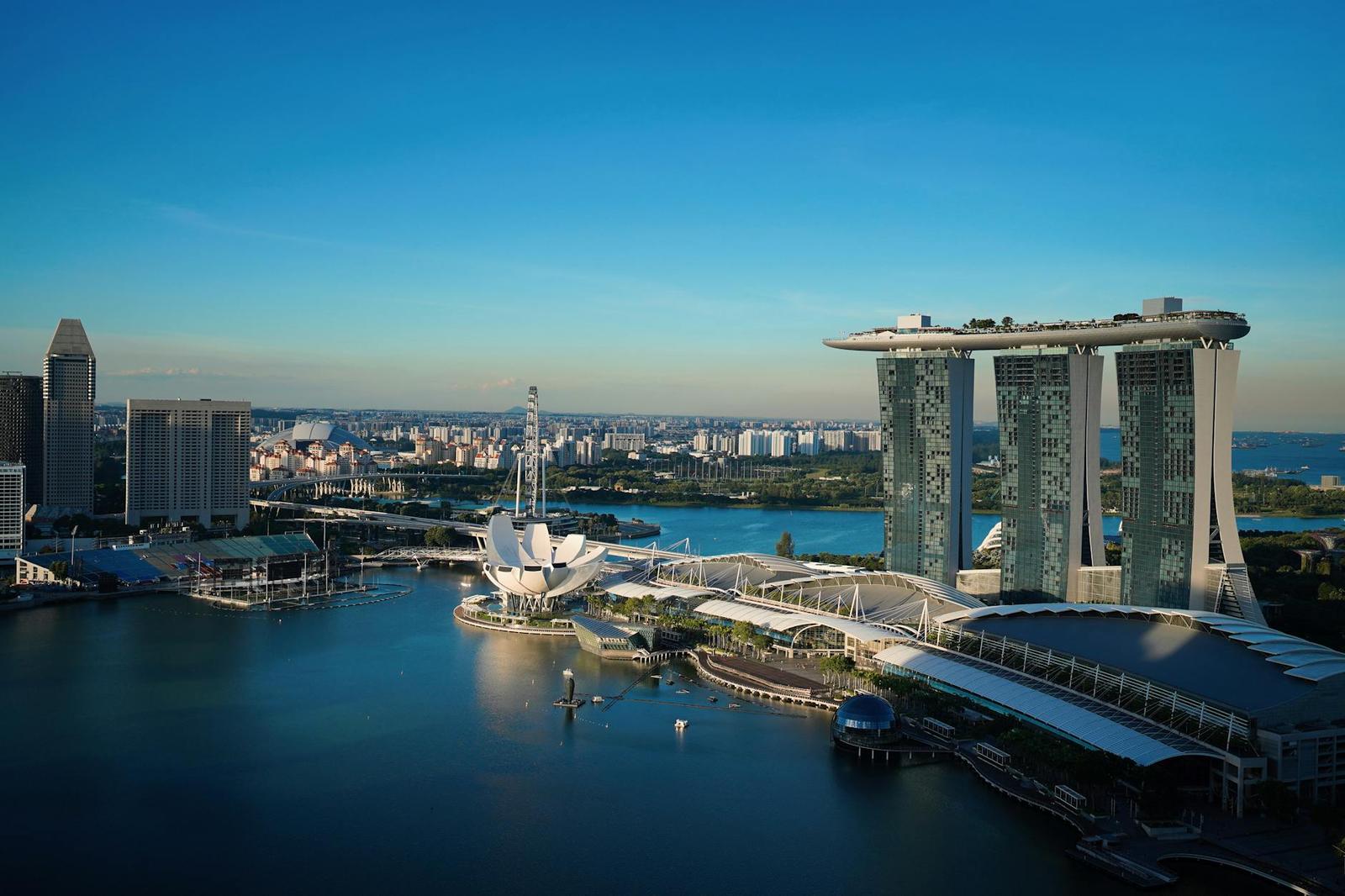 Marina Bay Sands' triple towers rise beside a waterfront park under a clear sky