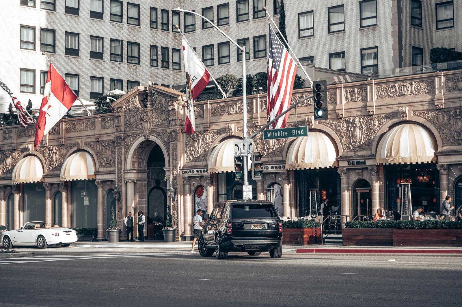 A striped-awning hotel facade with flags flying above a busy street corner