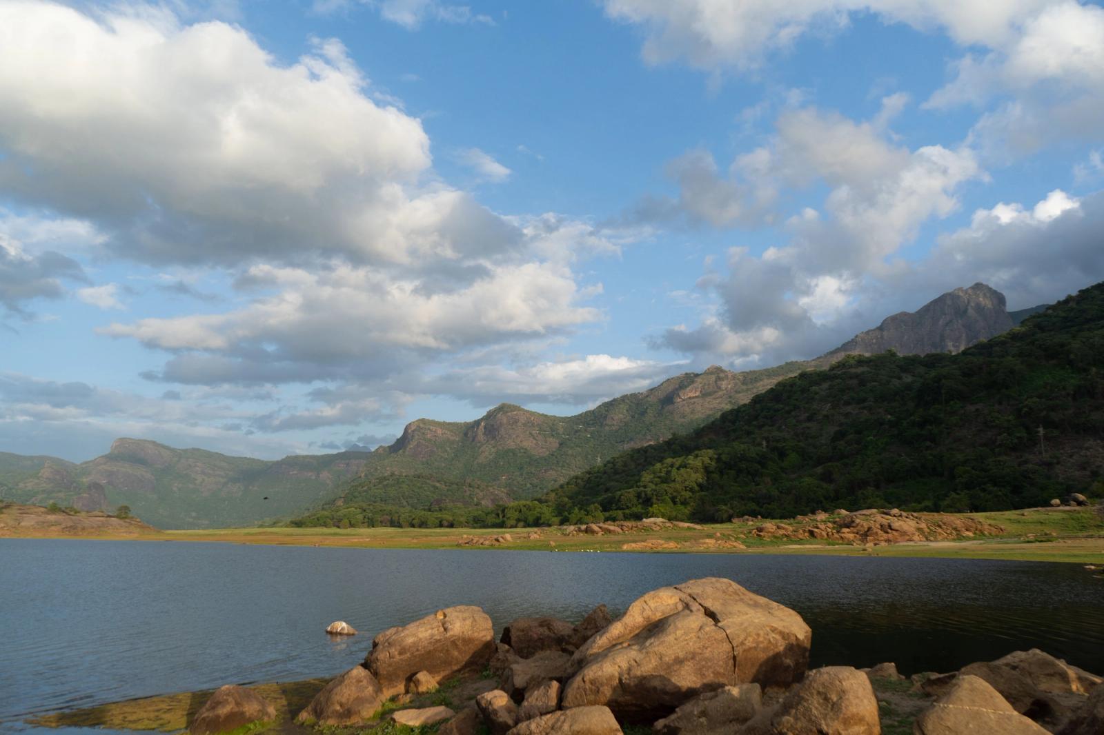 Beautiful landscape of Pollachi, TN, India featuring hills, a serene lake, and lush greenery under a blue sky