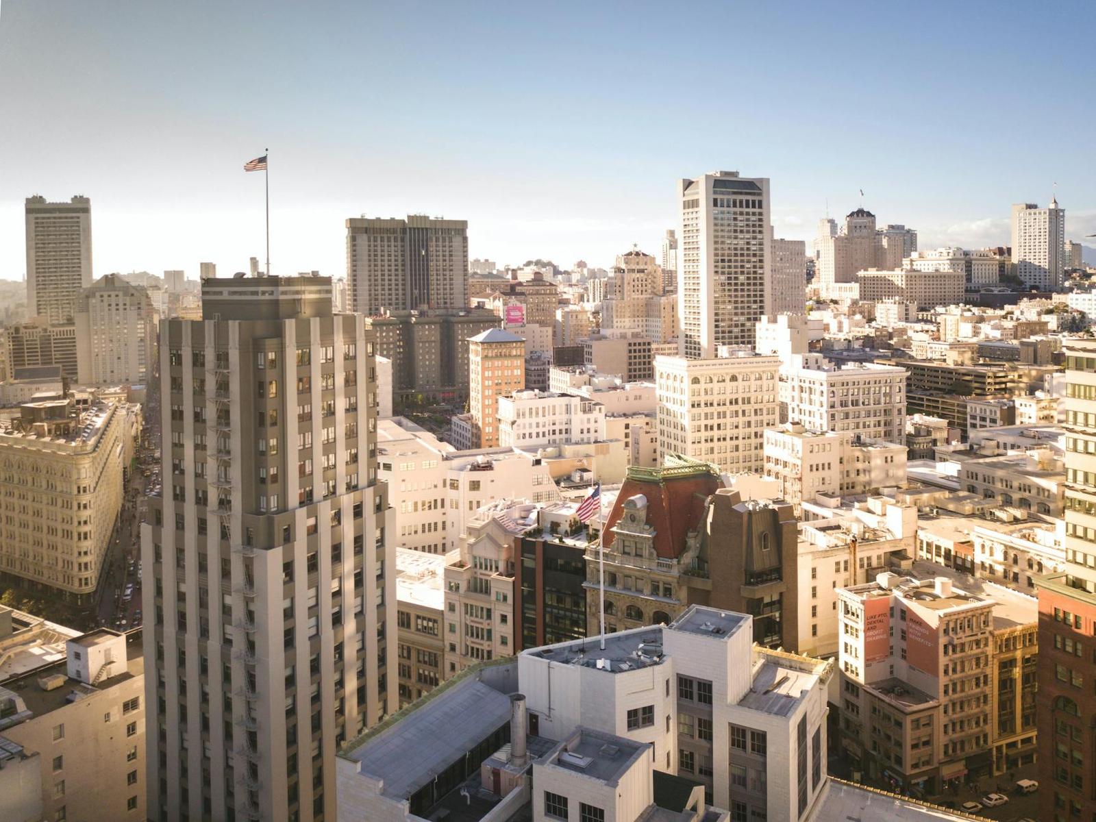 An aerial view of a dense downtown skyline with a flag atop one tower