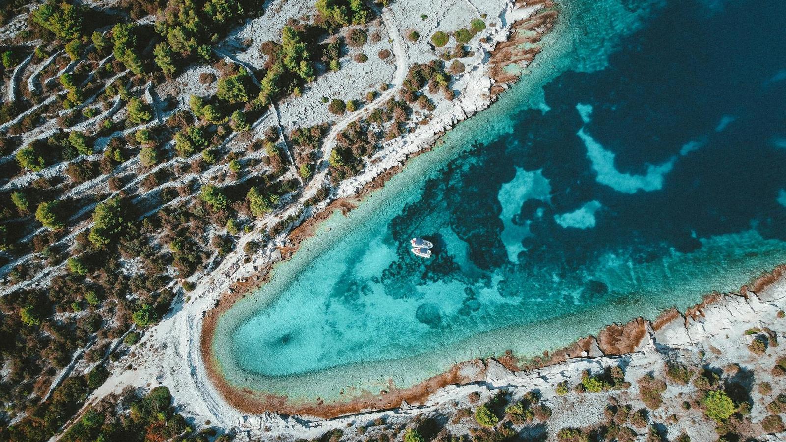 Aerial view of a turquoise lagoon fringed by white rocky shoreline