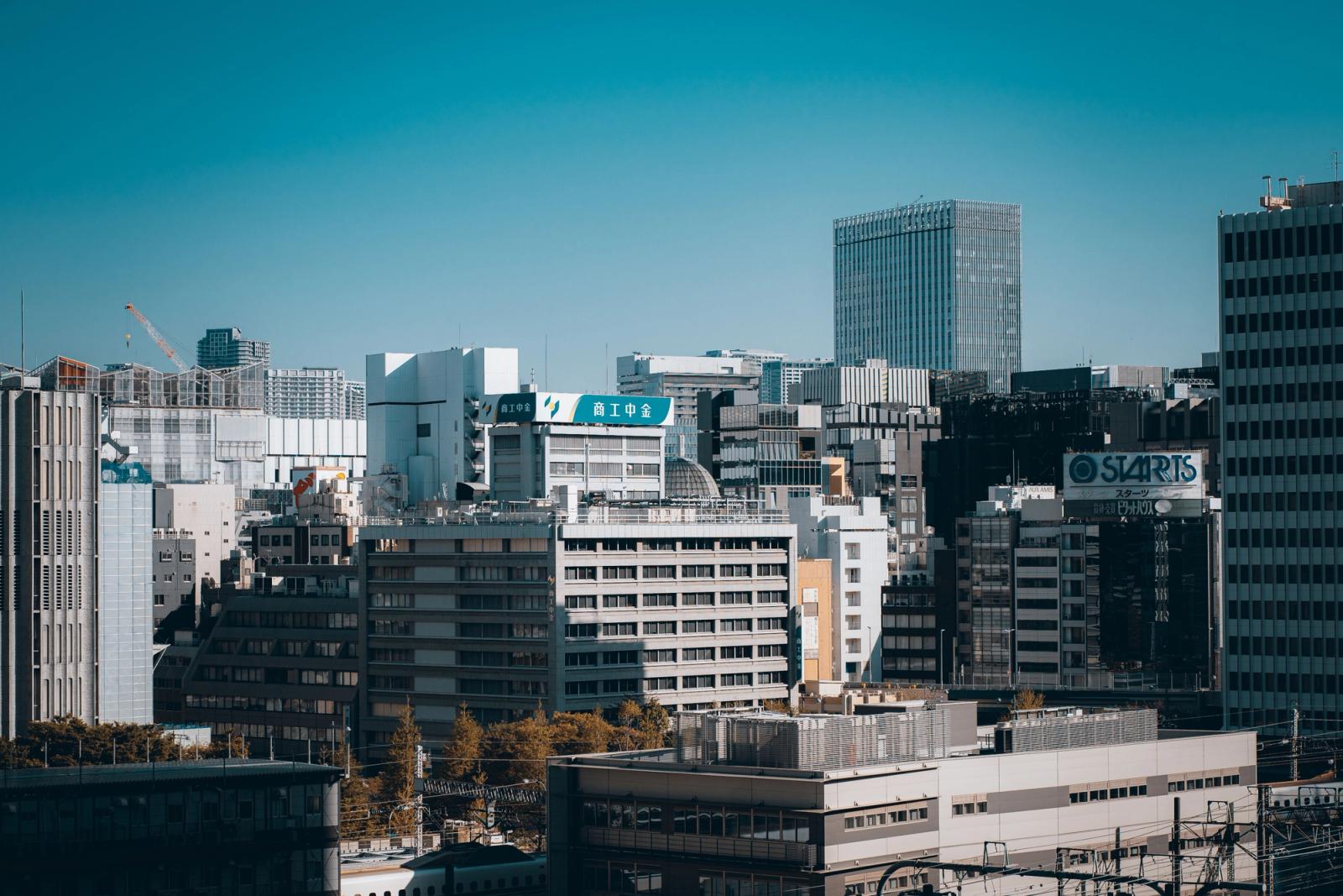 Aerial view of Tokyo's modern skyline features towering buildings and urban architecture under a clear blue sky