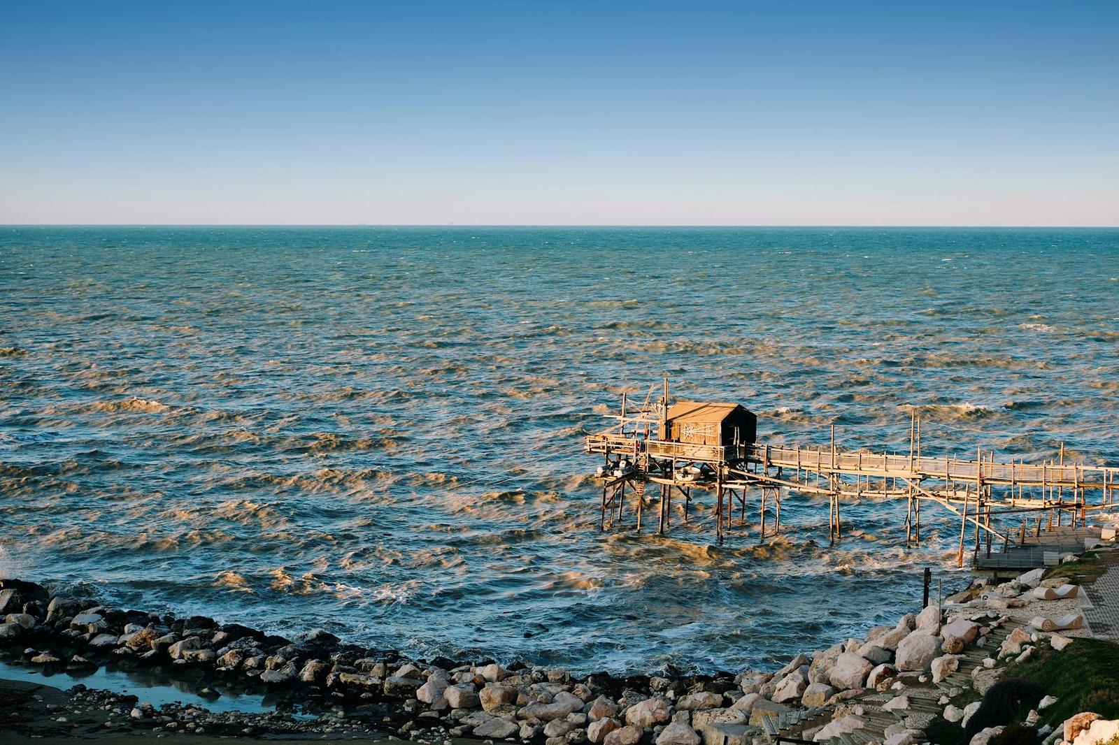 A wooden stilt fishing hut on a rippling turquoise sea