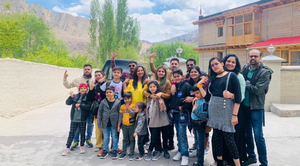 A cheerful family group posing outdoors with mountains in the background.