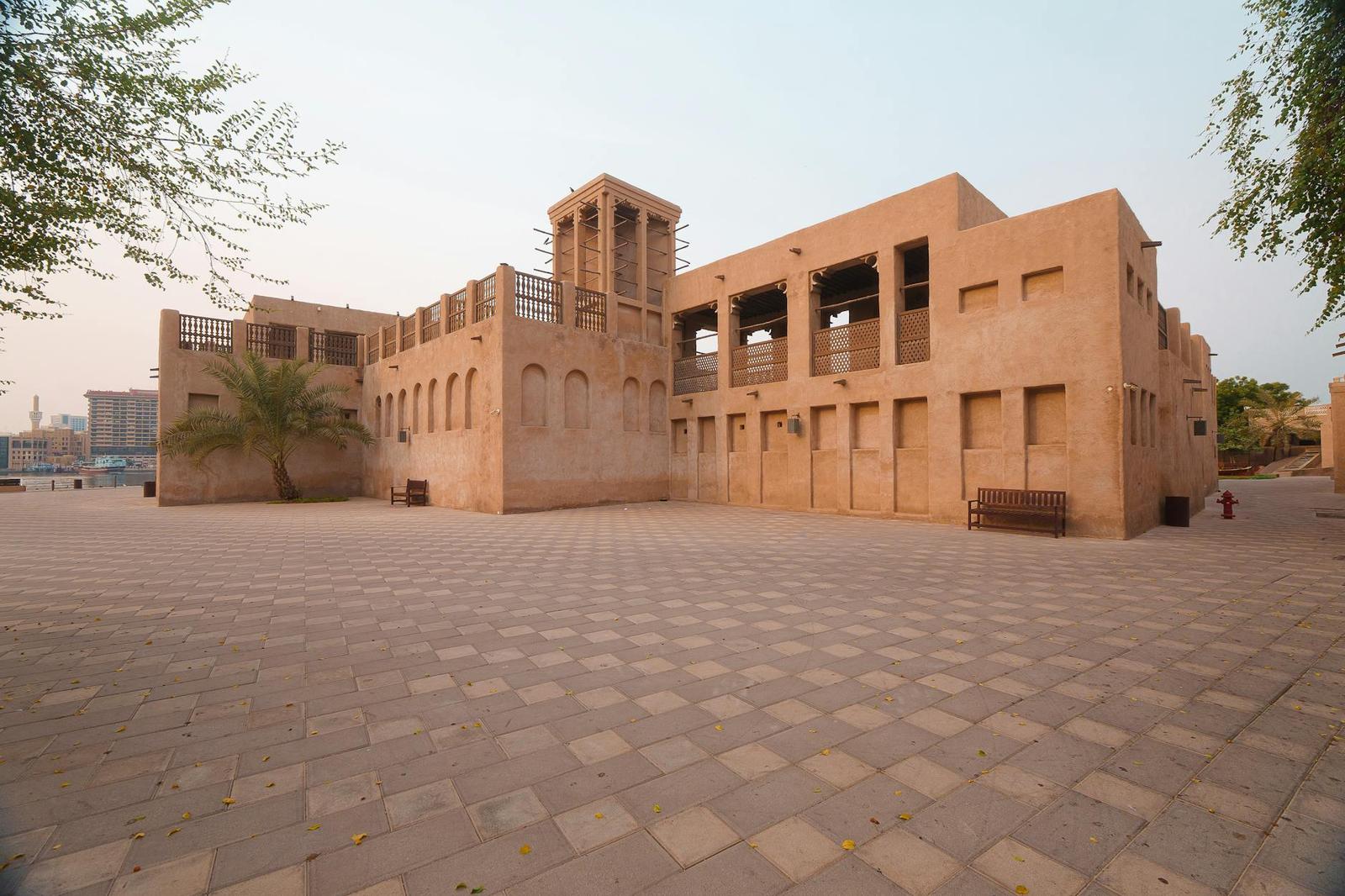 A sandstone building with a traditional windtower in an empty courtyard