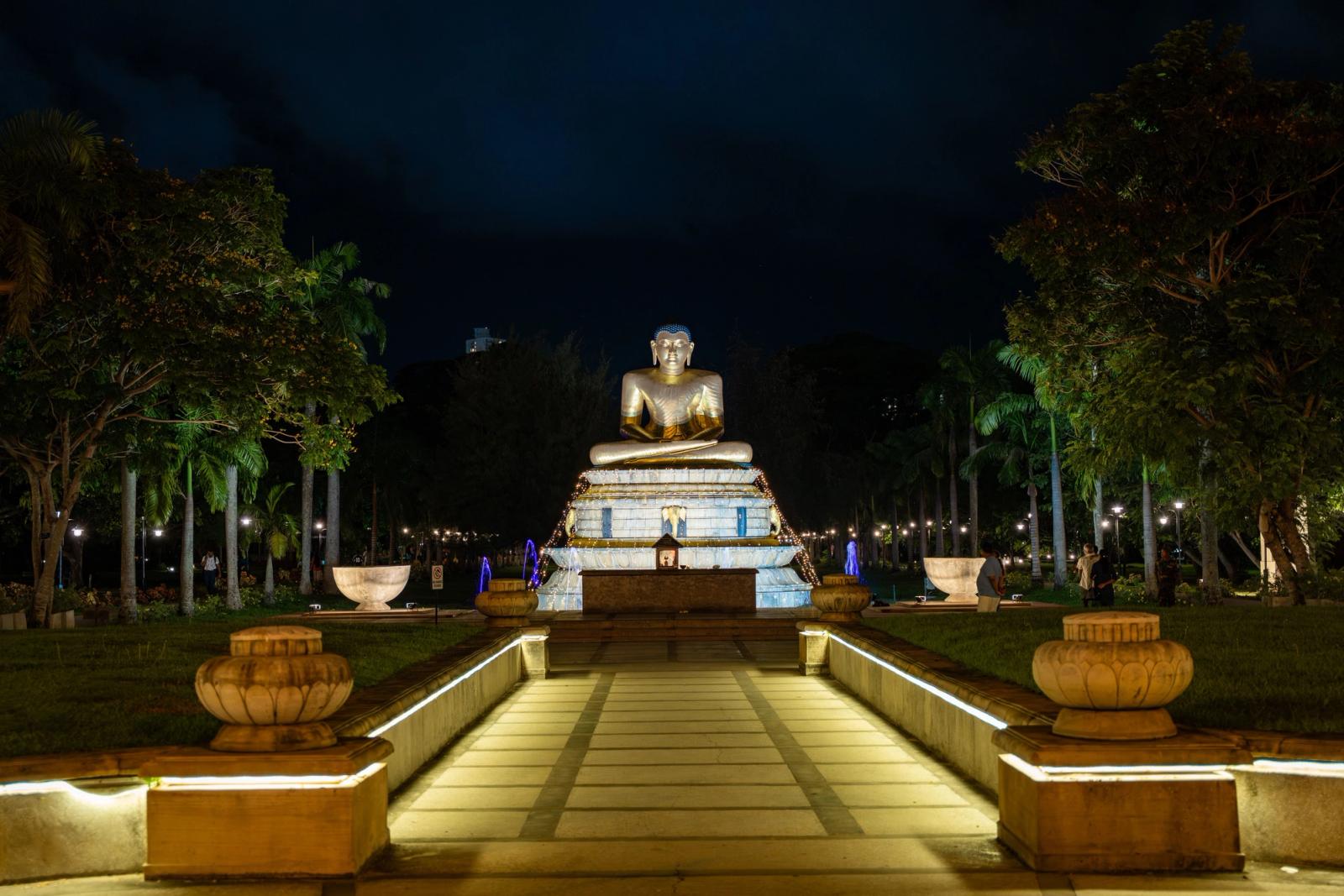 Illuminated Buddha statue at Seema Malaka Temple, Colombo, during a serene night, surrounded by lights and nature