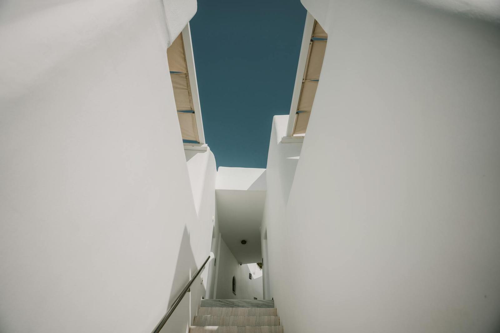A narrow whitewashed staircase passage opening to blue sky