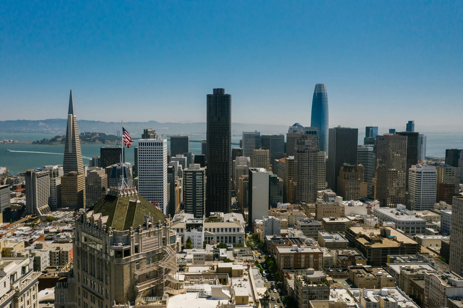 Aerial view of a hilly city skyline with a tall pyramid-shaped tower