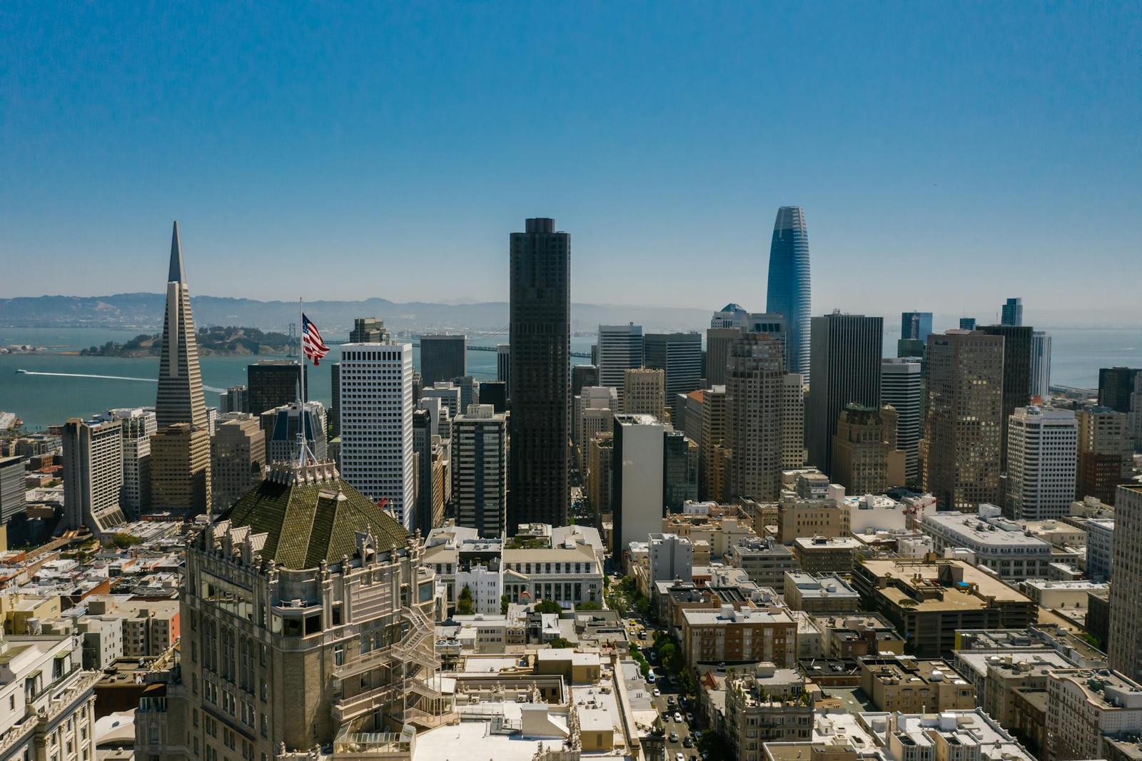 Aerial view of a hilly city skyline with a tall pyramid-shaped tower