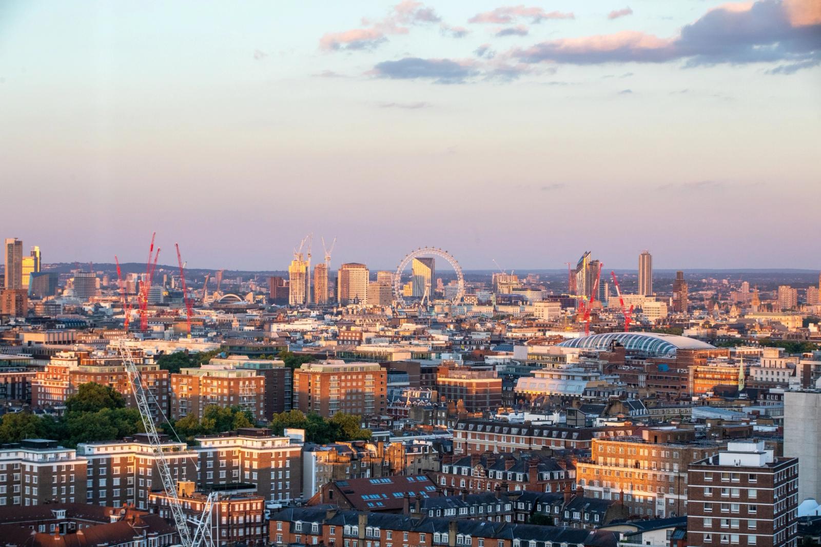 Aerial view of London's cityscape featuring the London Eye during sunset