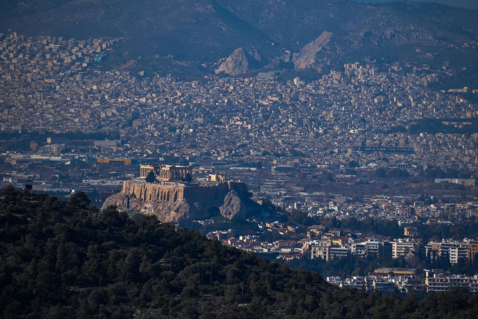 Stunning aerial shot of Athens cityscape with the Acropolis prominently visible, surrounded by urban sprawl and mountains