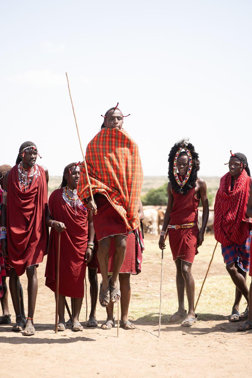Group of Maasai men in red plaid shawls and beaded jewellery standing on the plain