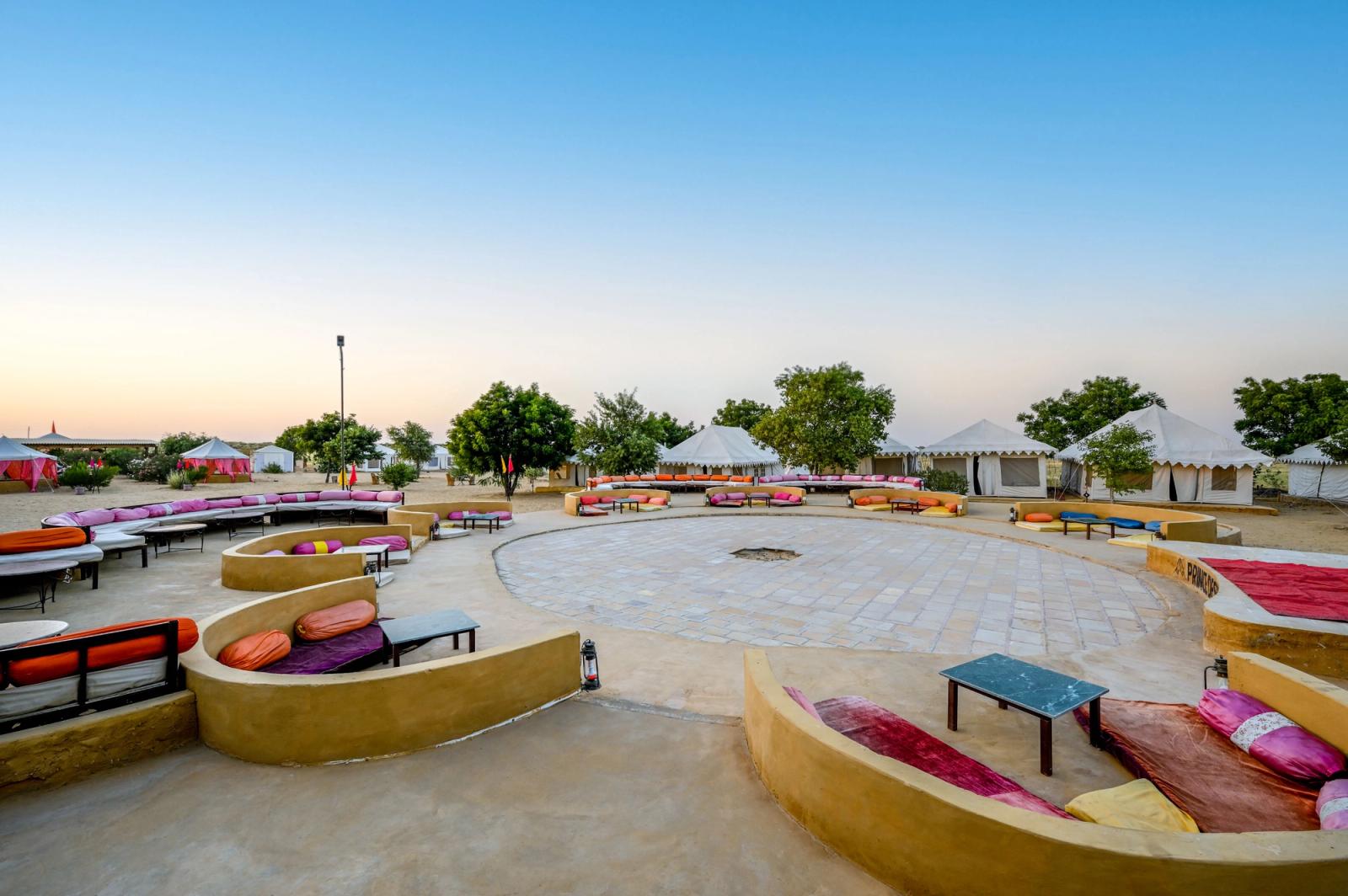 A vibrant desert camp with colorful seating and tents in Jaisalmer, India, under a clear sky