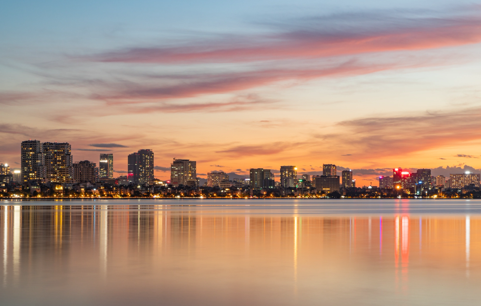 Captivating sunset view of Hanoi's skyline reflecting in the tranquil waters