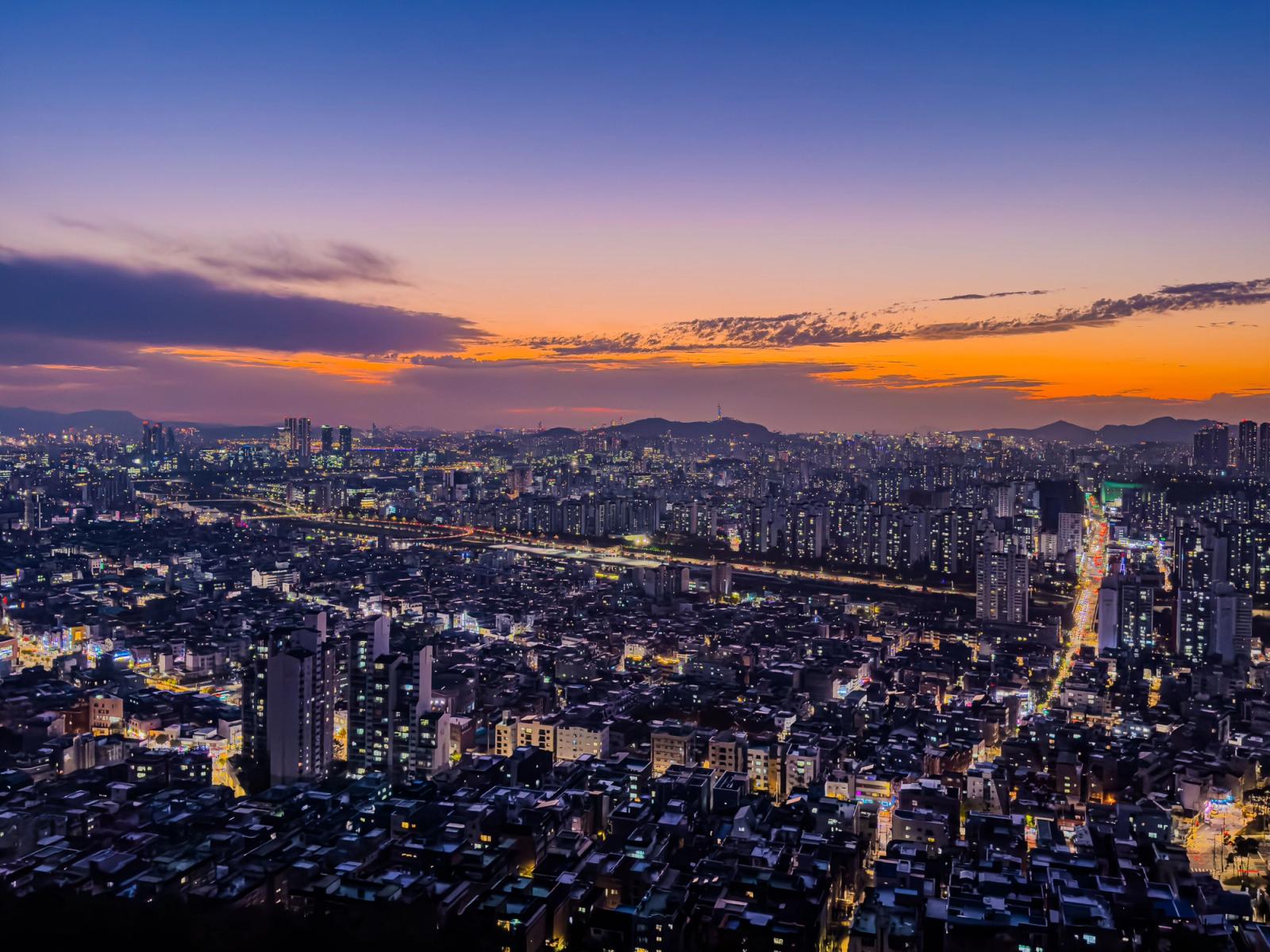 Breathtaking aerial view of Seoul at sunset, showcasing vibrant city lights and skyline