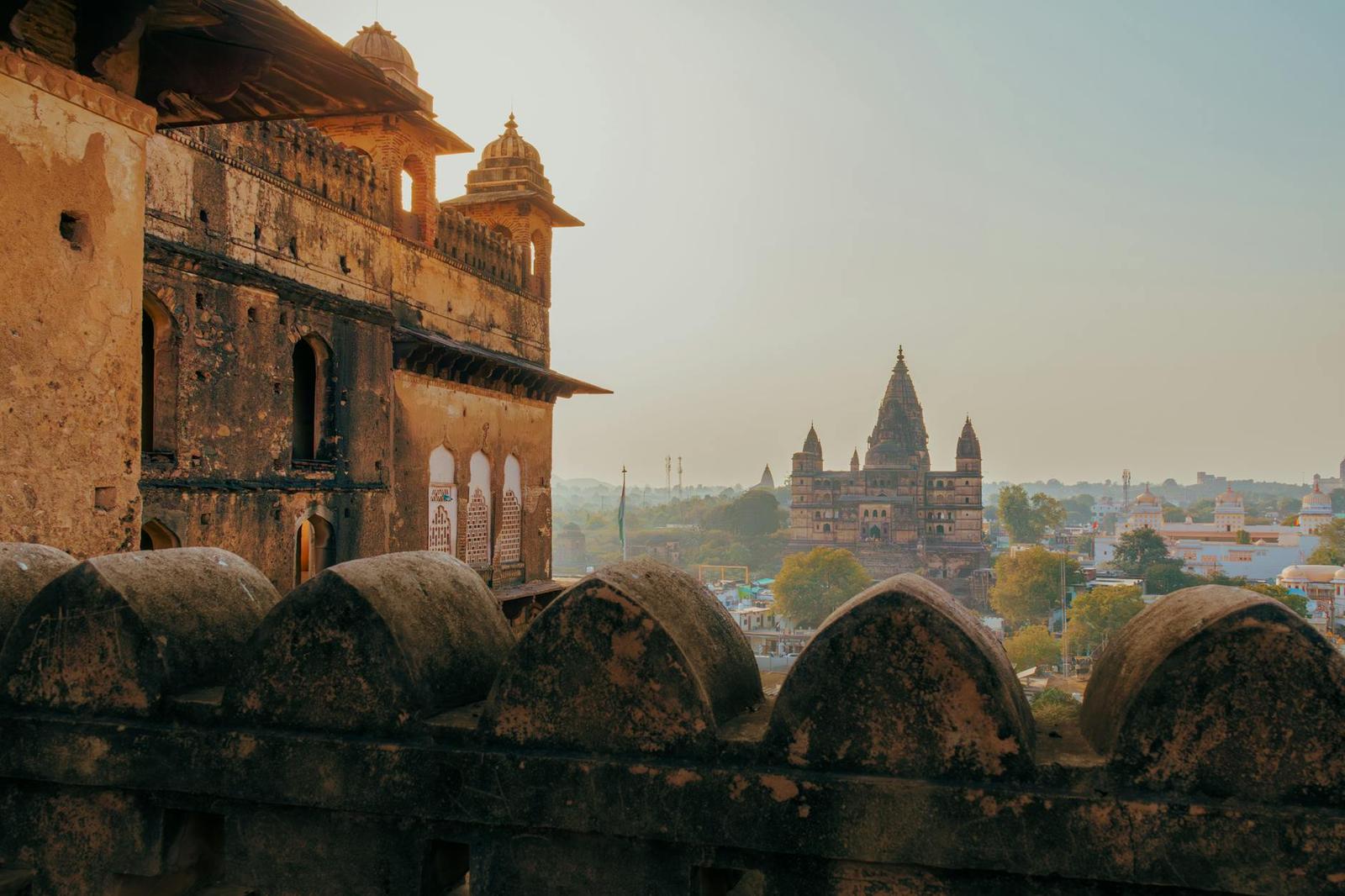 A fort tower overlooking a distant temple spire across a hazy town