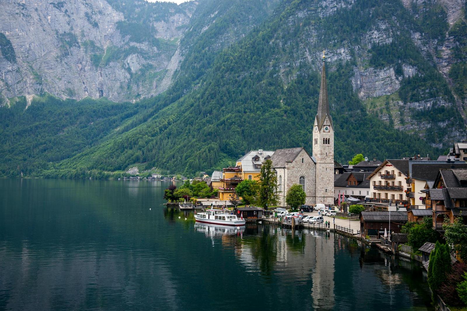Picturesque view of Hallstatt with a church by the lake surrounded by mountains