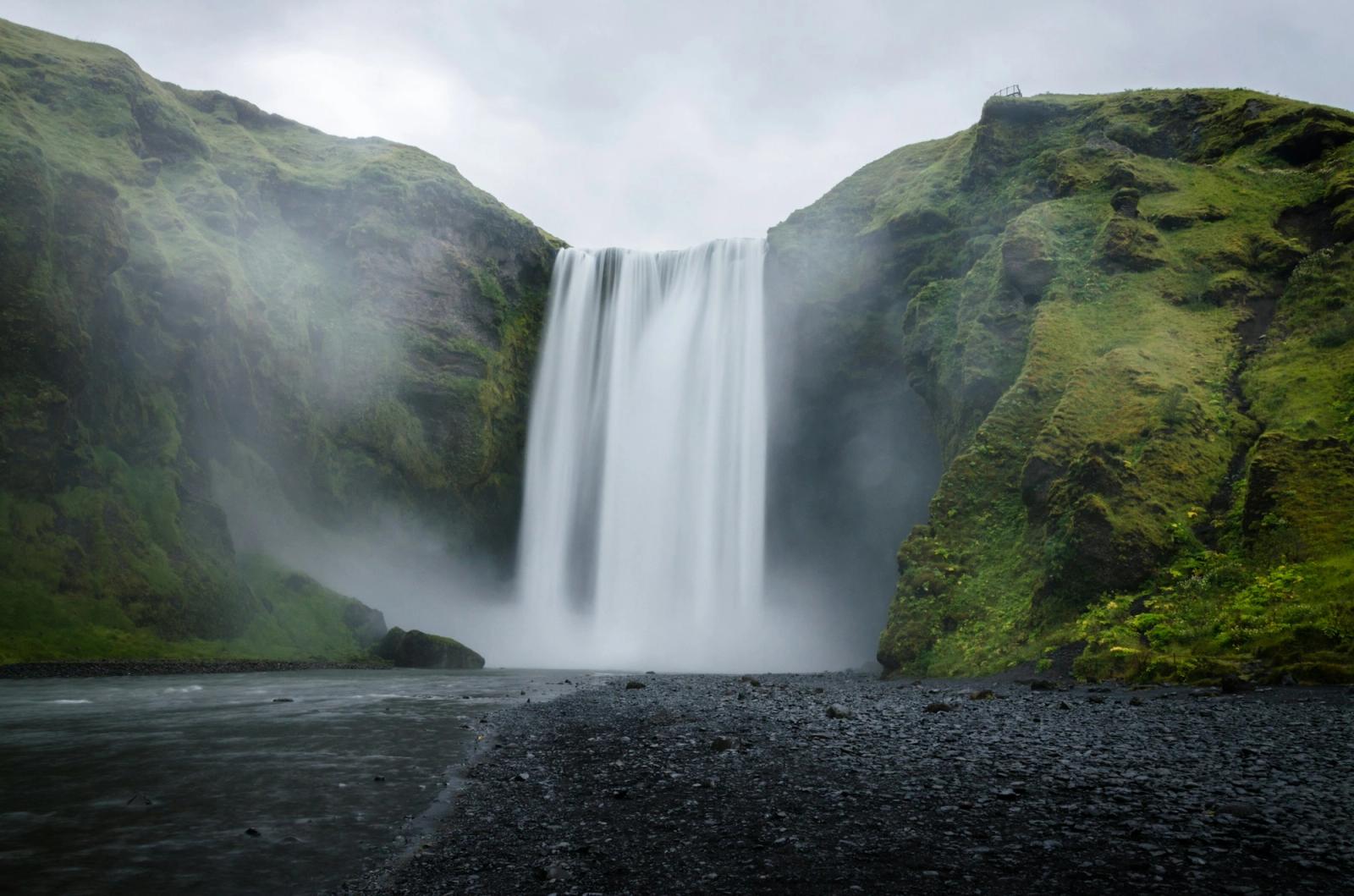 A tall waterfall cascading between moss-covered cliffs
