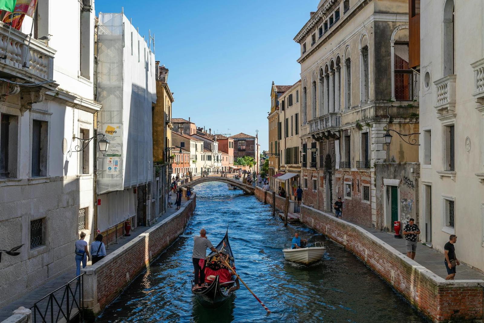 Scenic view of a gondola navigating a narrow canal in Venice, Italy, flanked by historic architecture