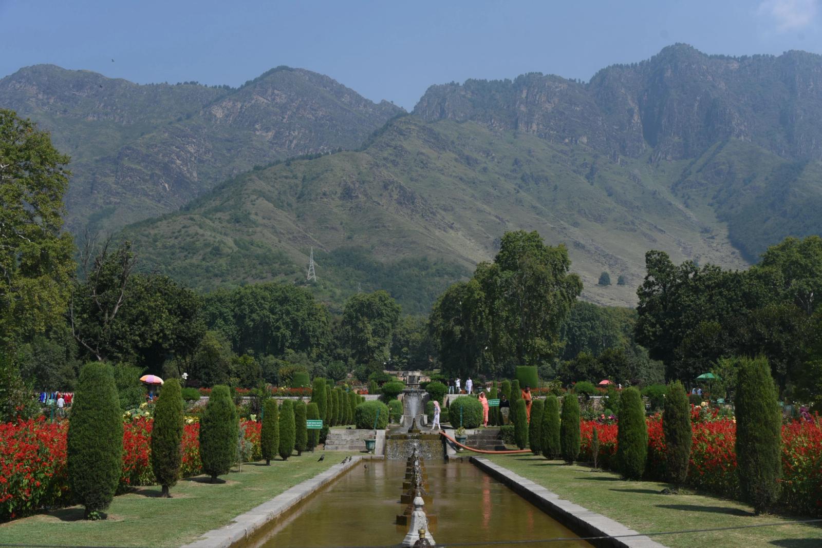 Beautiful Mughal garden in Srinagar with red flowers and mountains under a clear blue sky