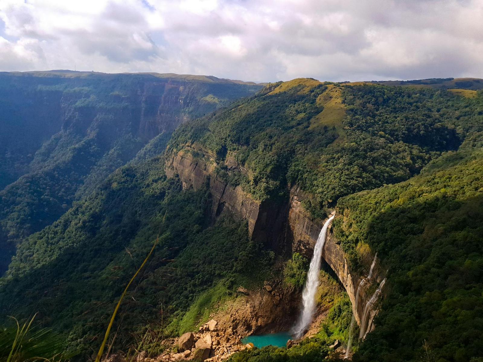 A breathtaking aerial view of a waterfall cascading down lush green hills in Meghalaya, India