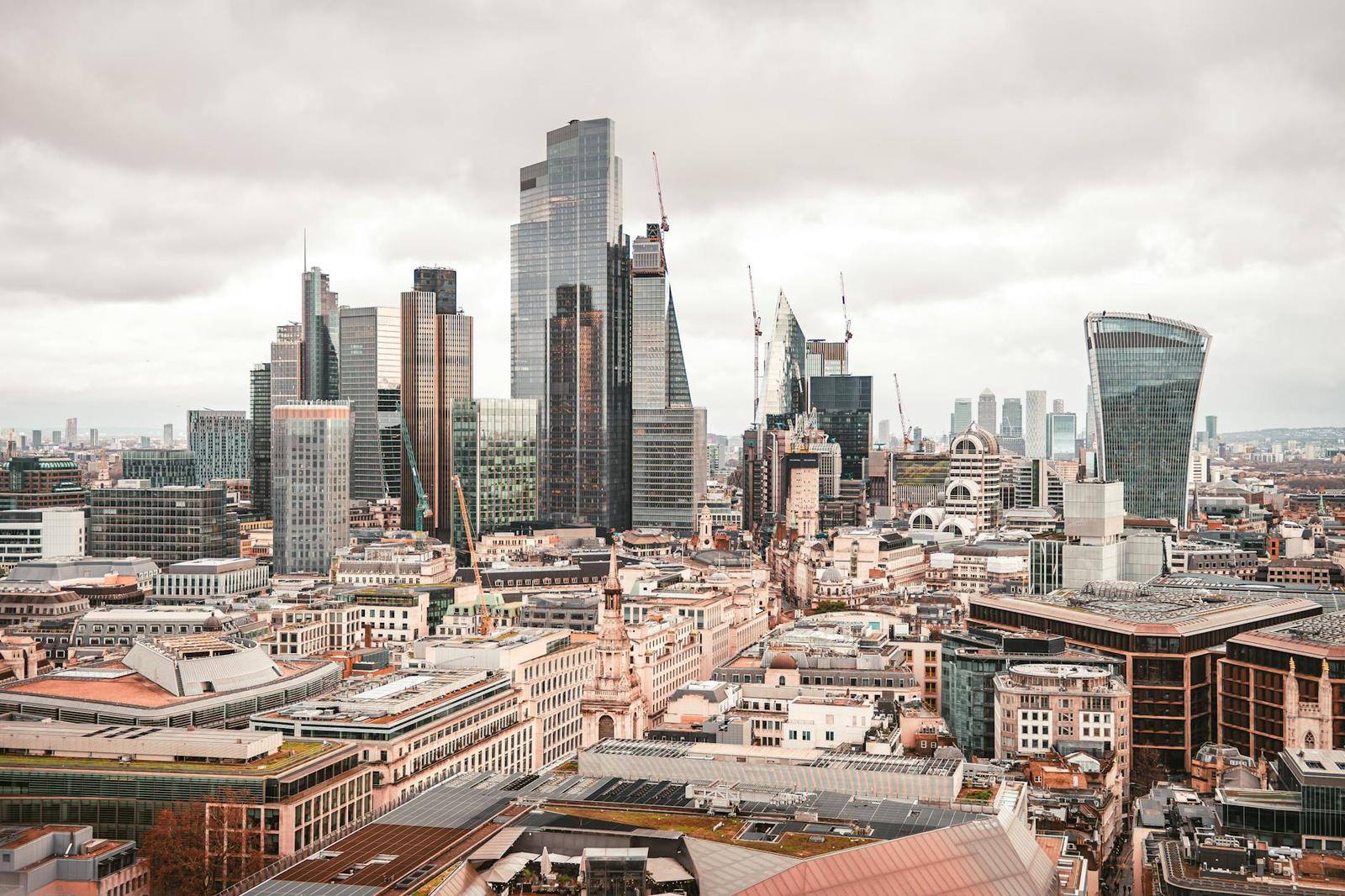 A cluster of modern skyscrapers rising above older rooftops under an overcast sky