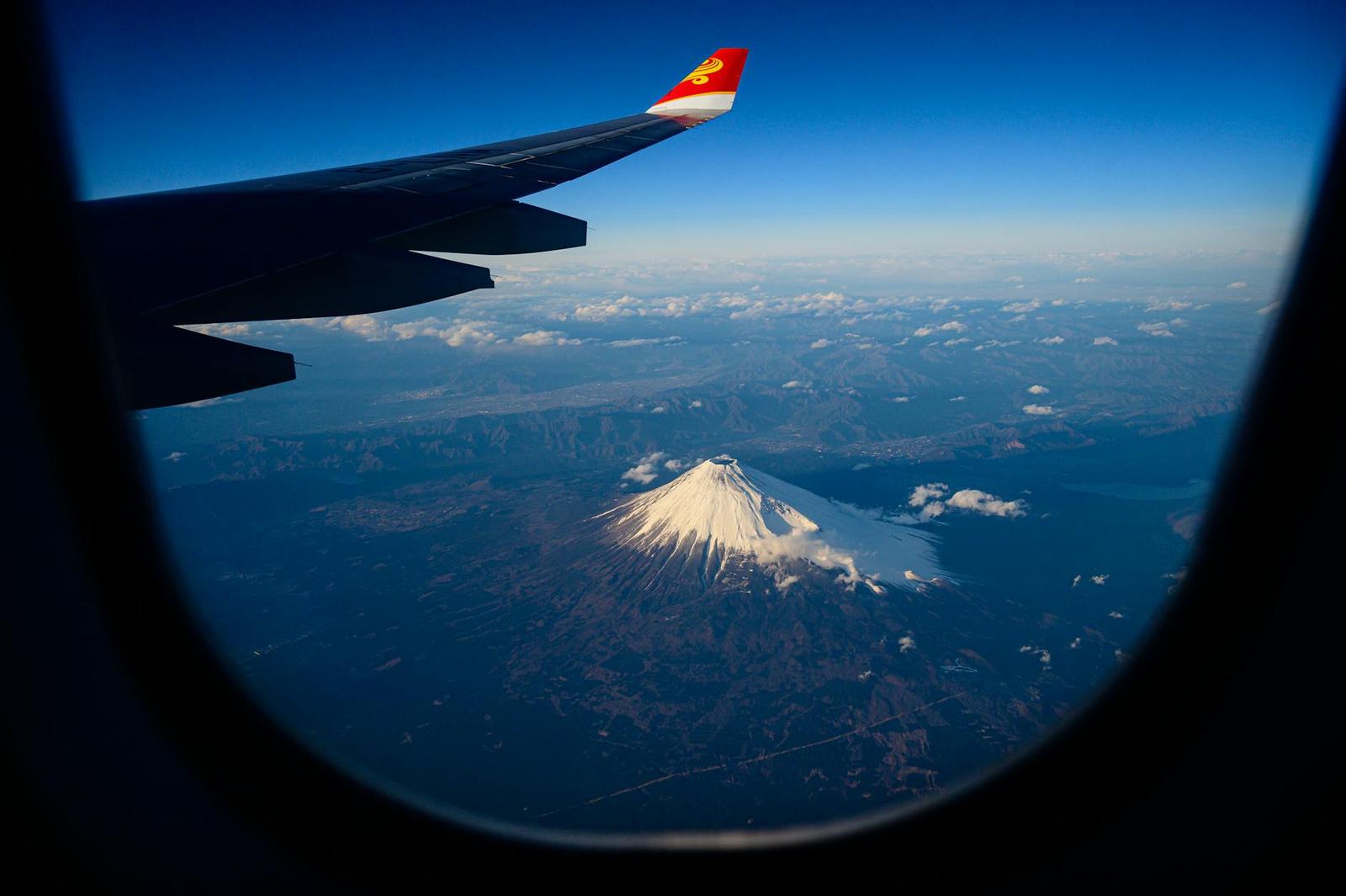 View from an aeroplane window over a snow-capped volcanic peak