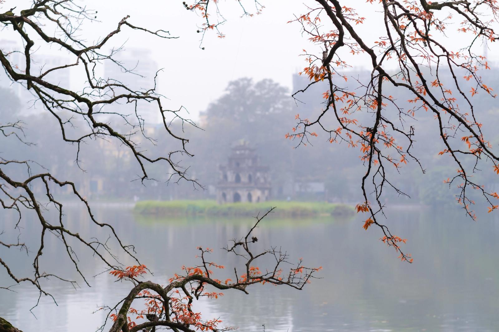 Serene autumn scenery at Hoan Kiem Lake with Turtle Tower and colorful branches