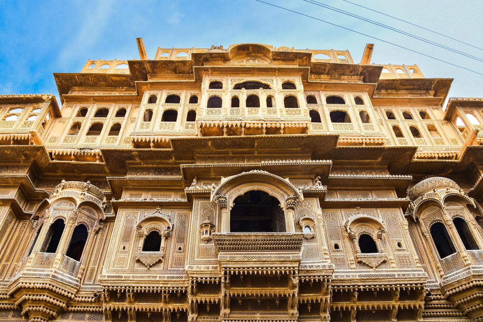 A detailed view of traditional Indian architecture with intricate carvings under a clear blue sky