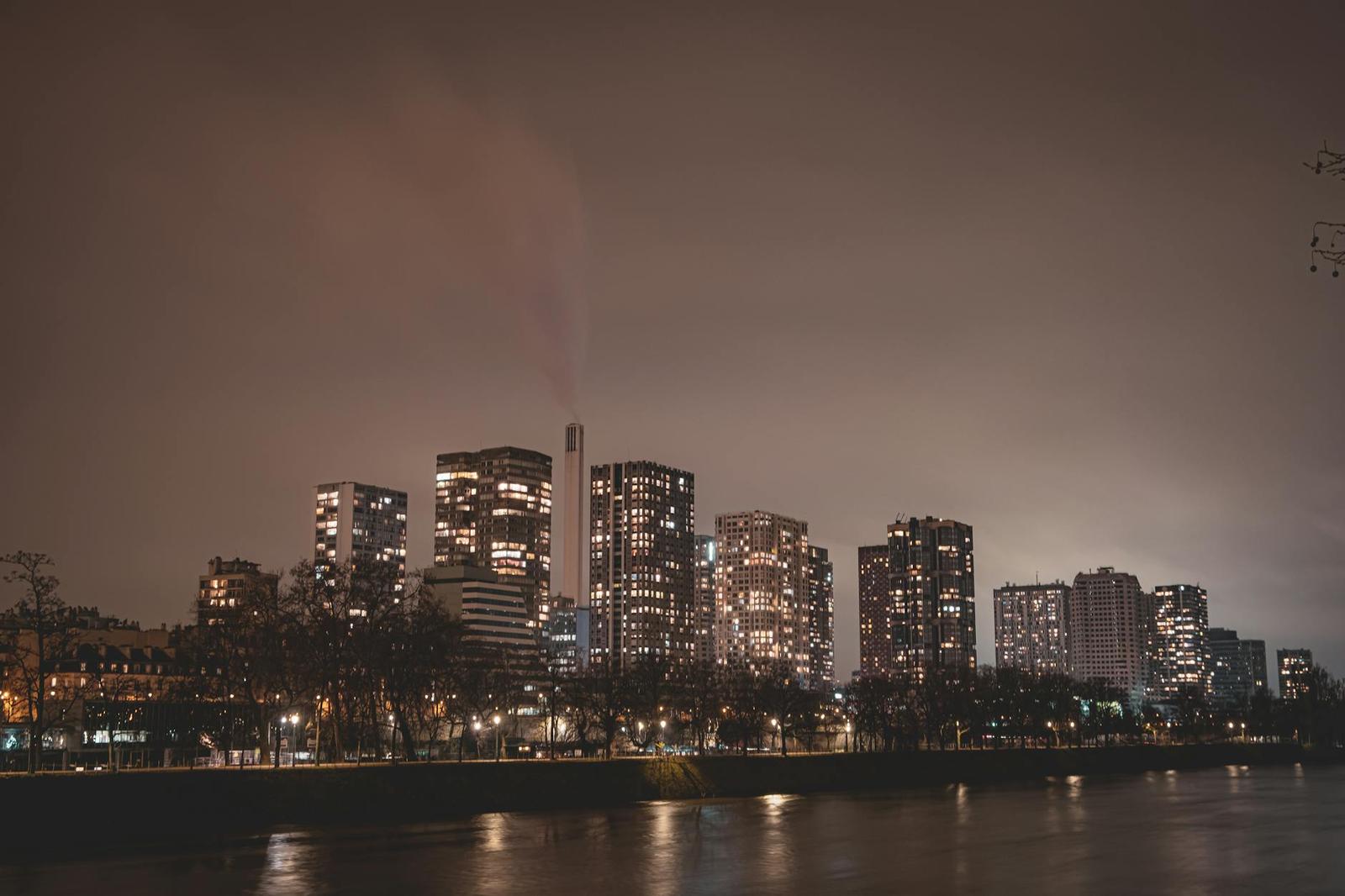 A city skyline lit up at night beside a dark river