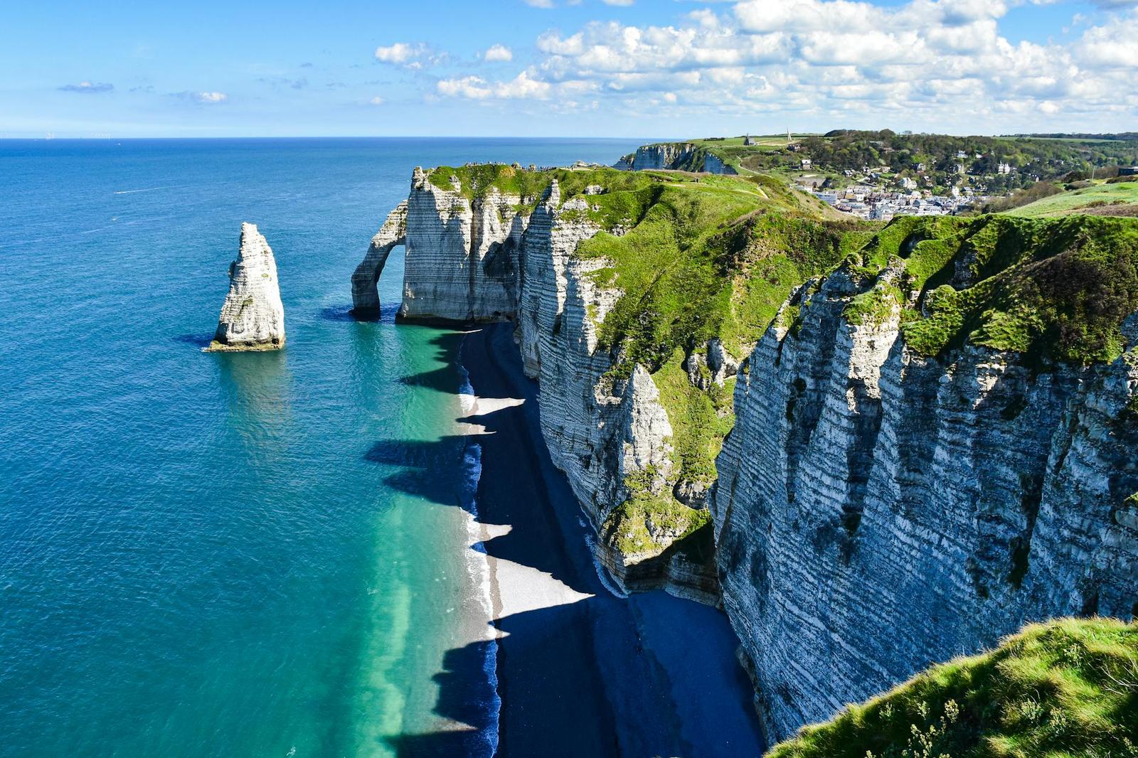 White chalk cliffs with a sea arch and rock pillar meeting turquoise water