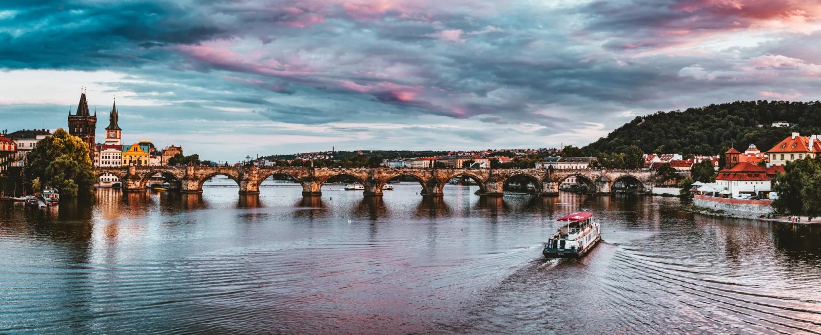 Stunning view of Charles Bridge with vibrant sunset hues over Vltava River in Prague