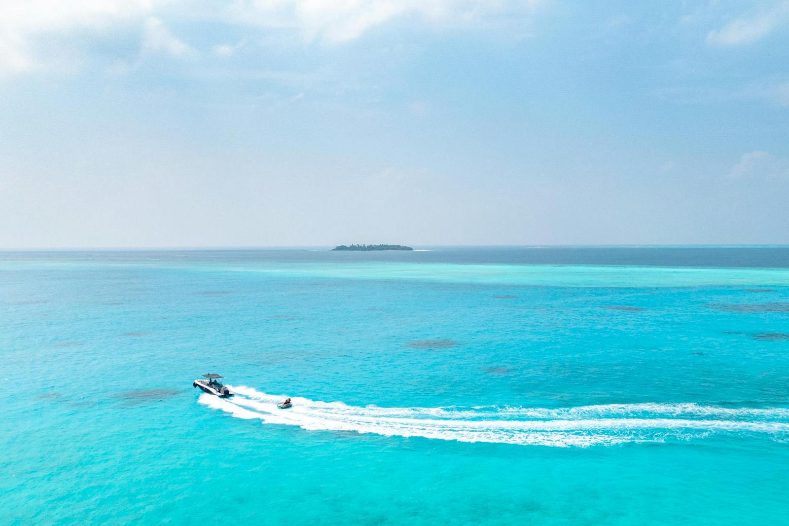 A speedboat leaving a long wake across a turquoise lagoon