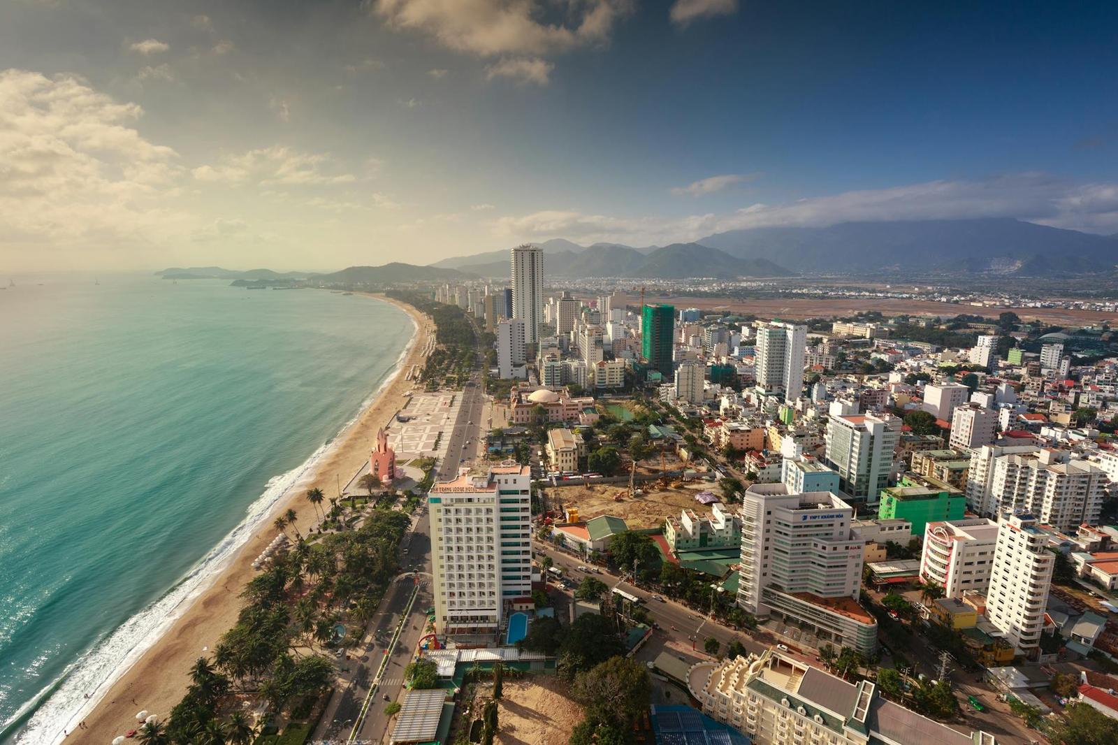 Aerial view of a coastal city skyline curving along a long sandy beach